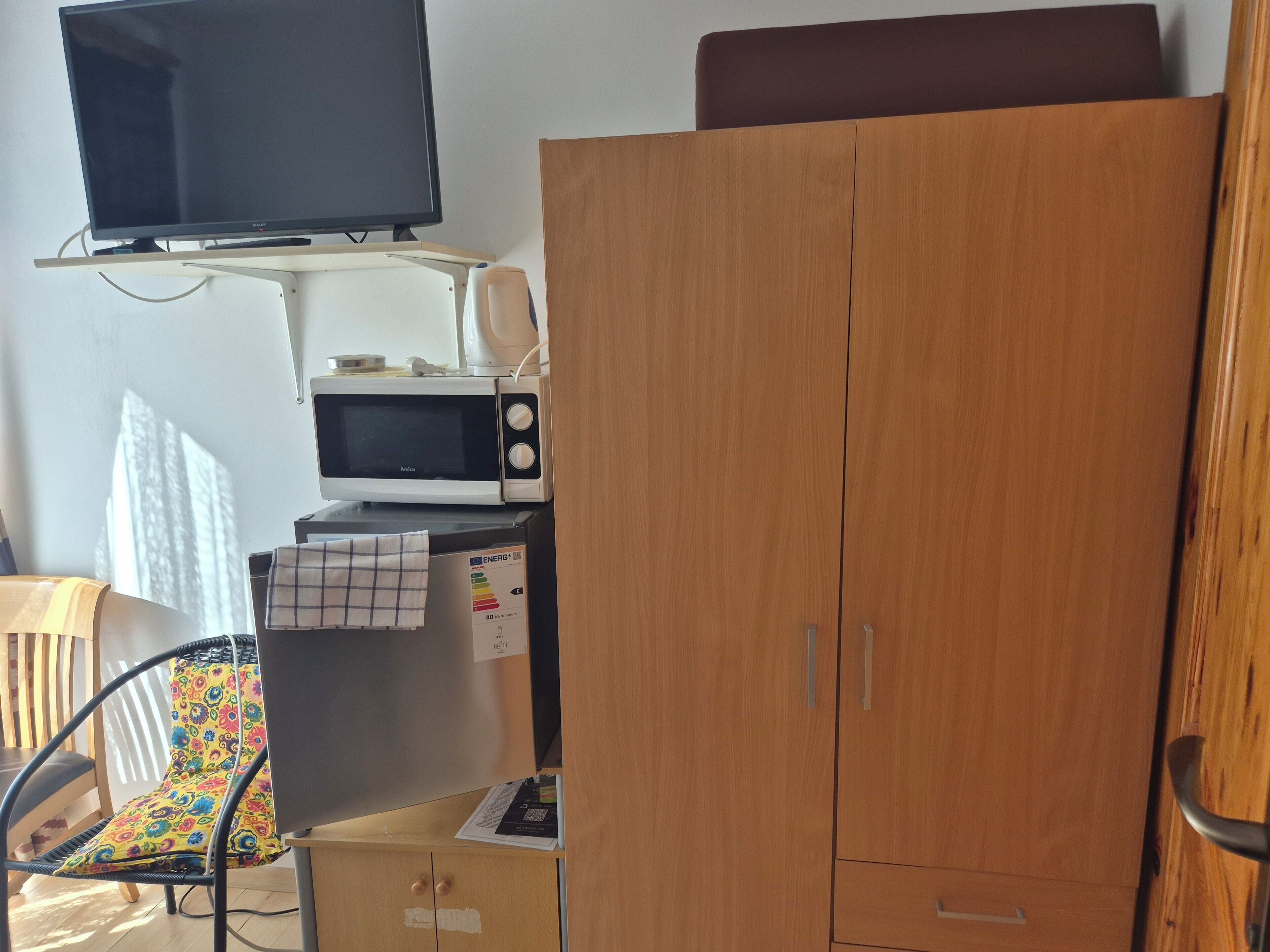 A room with a television, microwave, and a wardrobe.