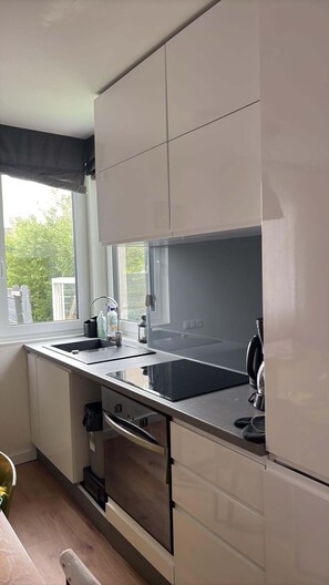 Et moderne køkken med et stort vindue, rustfrie hårde hvidevarer og en indbygget ovn.