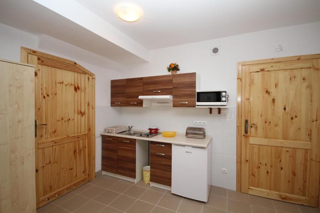 A compact kitchen with wooden cabinets, a microwave, a toaster, and a small sink.