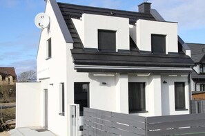 Et moderne hus i to etager med hvide facader, sort tag og en parabolantenne.