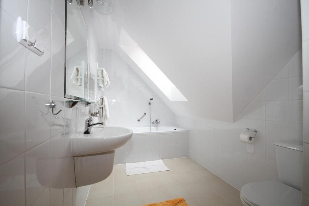 A modern bathroom with a sink, mirror, bathtub, and toilet.