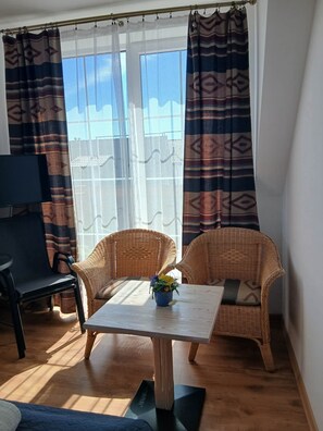 A room with wicker furniture, a table with a vase, and a TV.
