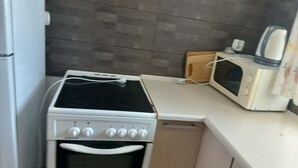 Keittiössä on liesi, uuni, mikroaaltouuni ja puinen leikkuulauta.
