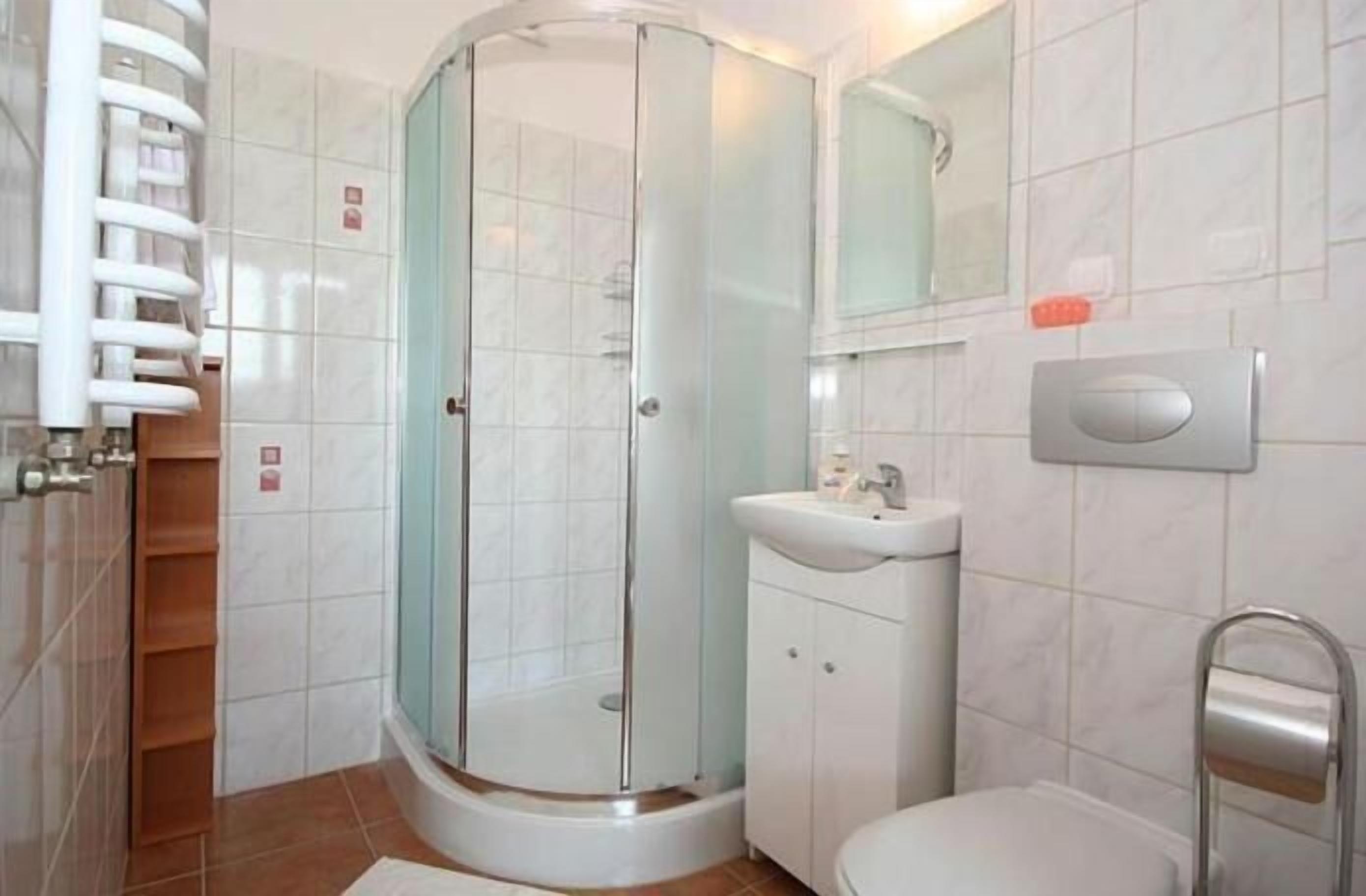 A bathroom with a glass-enclosed shower, a sink, and a toilet.