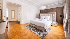 A modern bedroom with a large bed, a wooden headboard, a bedside table, and a hanging light fixture. - Luxury - High-End - Champs-Élysées - Paris 8 - AC (Paris)