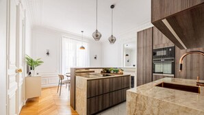 A modern kitchen with wooden cabinetry, a marble countertop, and pendant lighting. - Luxury - High-End - Champs-Élysées - Paris 8 - AC (Paris)