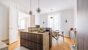 A modern kitchen with a central island, wooden flooring, and pendant lighting. - Luxury - High-End - Champs-Élysées - Paris 8 - AC (Paris)