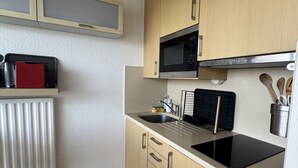 Ett kompakt kök med mikrovågsugn, diskho och träskåp.