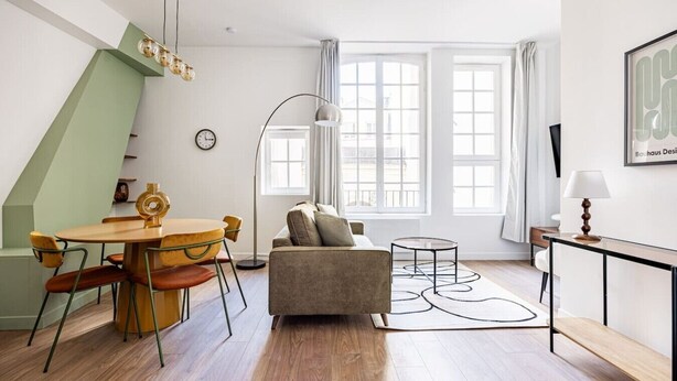 Een moderne woonkamer met een eethoek, grote ramen en een klok aan de muur.