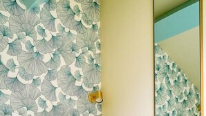 A bedroom with a bed, a mirror, and a wall with a leafy pattern. - 4D. Modern - 2 People - 1 Bedroom - Business - Paris 15 - AC (Paris)