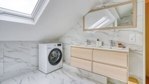 A modern bathroom with a skylight, a washing machine, a vanity with a mirror, and marble flooring. - 4D. Modern - 2 People - 1 Bedroom - Business - Paris 15 - AC (Paris)