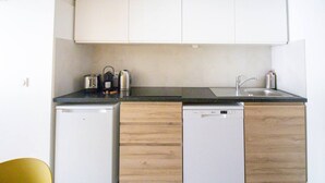 Eine kompakte Küche mit weißen Schränken, einer schwarzen Arbeitsplatte und einem Geschirrspüler.
