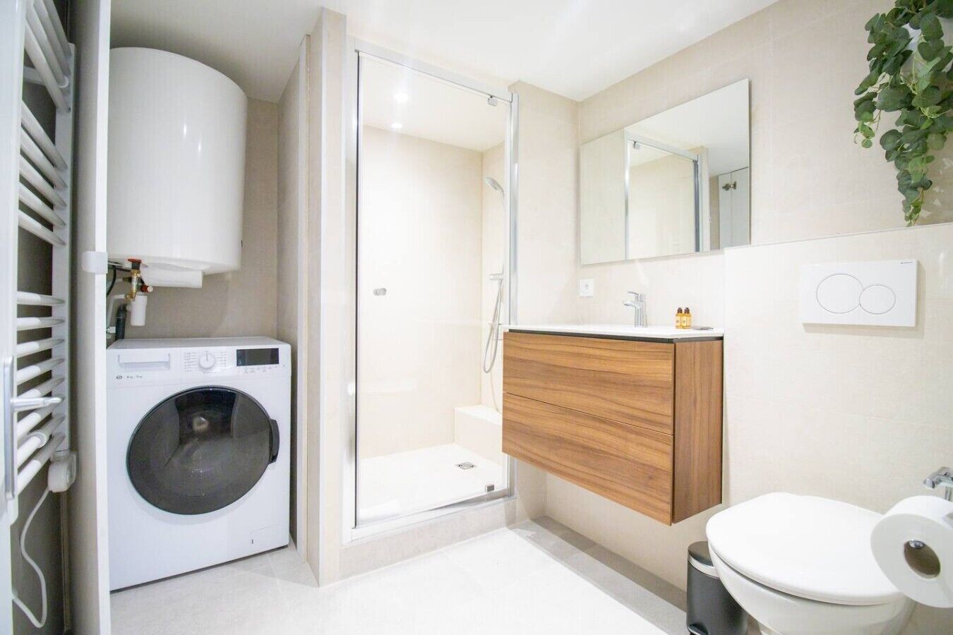 Un baño moderno con lavadora, ducha, inodoro y tocador de madera.