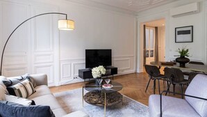 A modern living room with a sofa, a coffee table, a TV, and a dining area with chairs. - A3. Champs-Élysées#4-bedroom#Arc de Triomphe#AC (Paris)