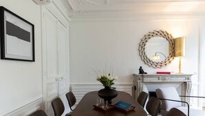 A dining room with a round table, chairs, a vase with flowers, a book, a fireplace with a mantle, and a wall-mounted mirror. - A3. Champs-Élysées#4-bedroom#Arc de Triomphe#AC (Paris)