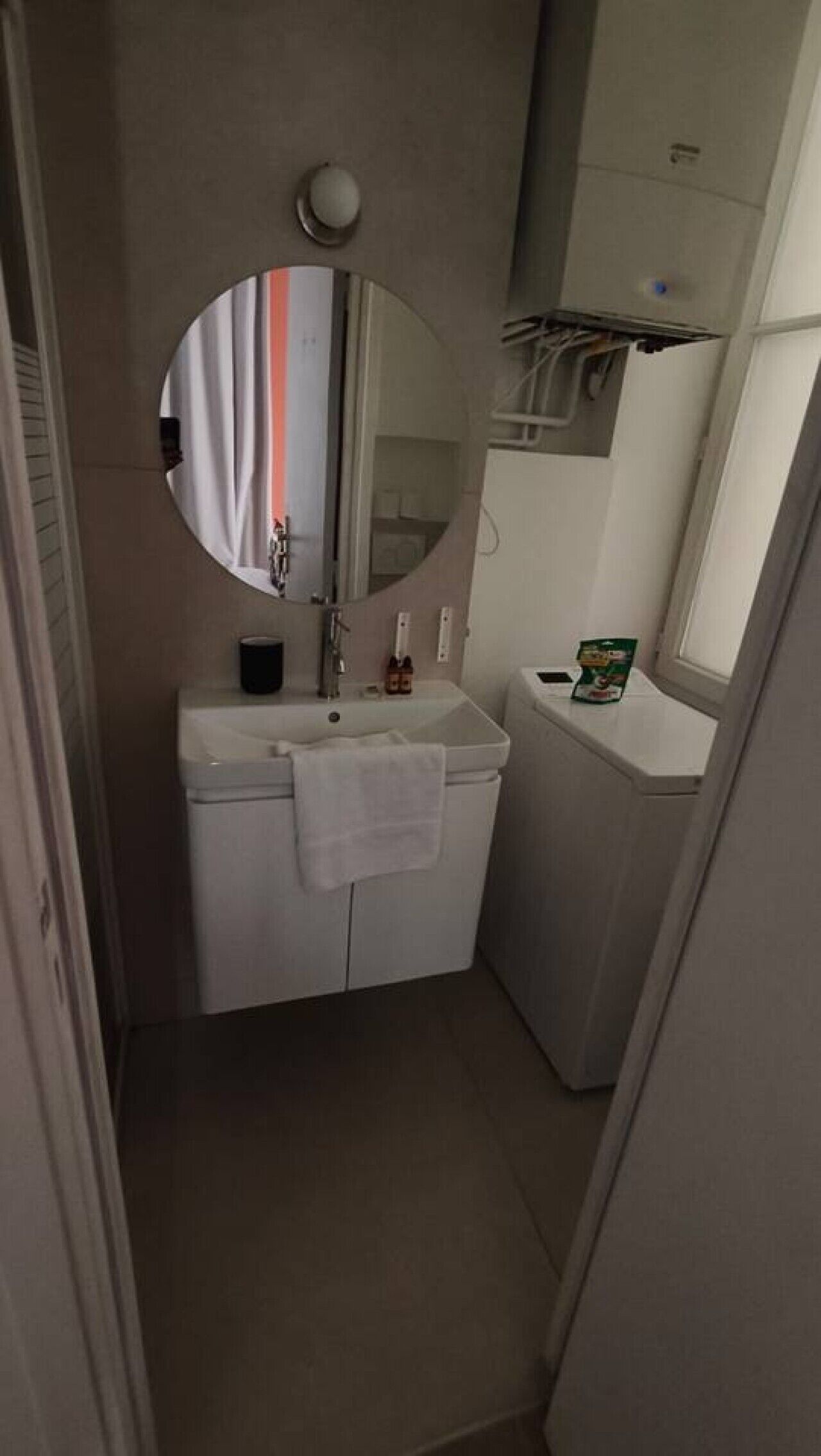 Une petite salle de bain avec un lavabo blanc, un miroir, une serviette et des toilettes.