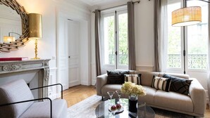 A living room with a sofa, a coffee table with flowers, a fireplace, and large windows. - A3. Champs-Élysées#4-bedroom#Arc de Triomphe#AC (Paris)