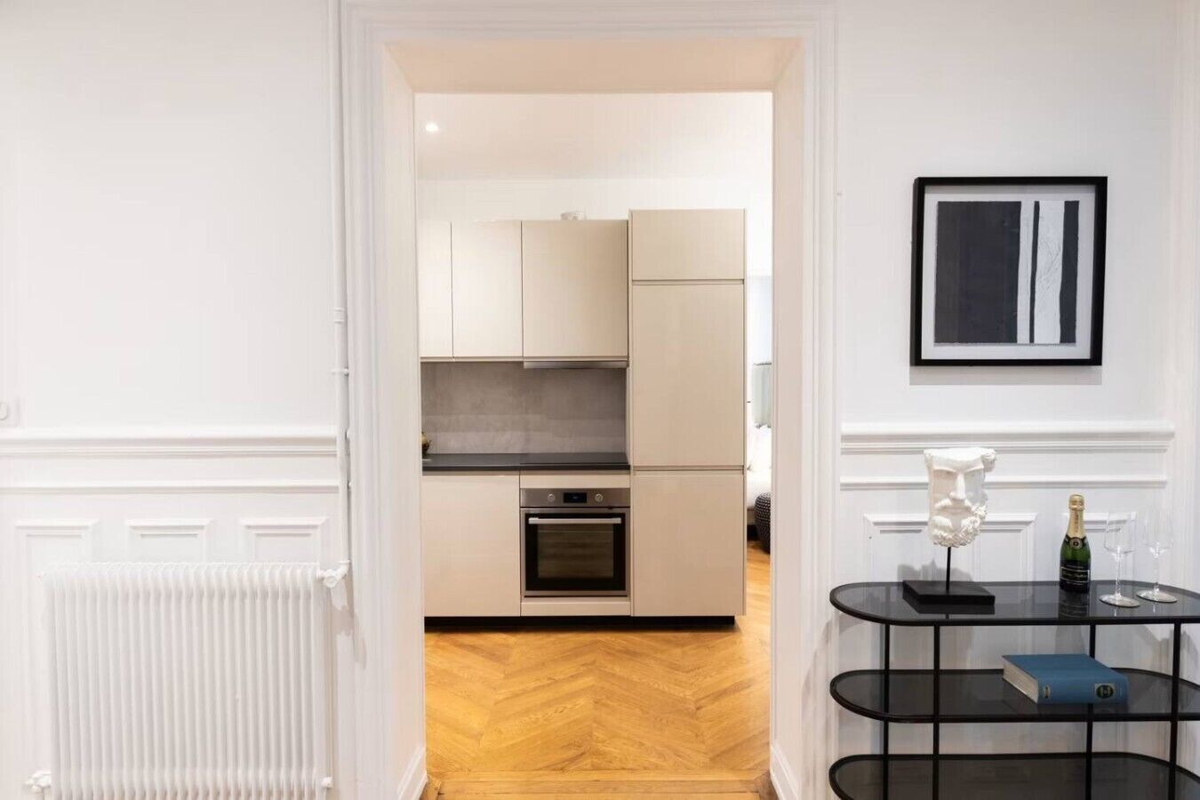 A modern kitchen with white cabinets, a built-in oven, and a black countertop.