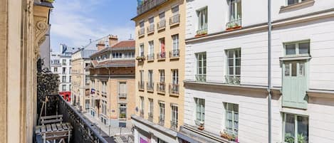 Una calle estrecha con edificios de varios pisos, balcones y una tienda con un letrero.