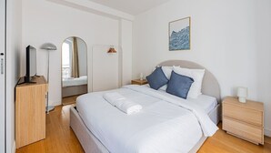 Une chambre à coucher avec un lit, des tables de chevet, un miroir, une lampe et un tableau au mur.