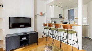 Un salon moderne avec un téléviseur à écran plat, un meuble de rangement en bois foncé et une table basse en verre.