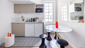 Uma cozinha moderna com lava-louças, micro-ondas e uma área de refeições com uma mesa redonda e banquetas.
