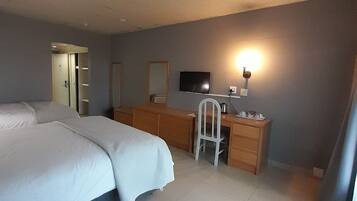 A hotel room with a bed, a desk, a chair, a television, and a mirror.