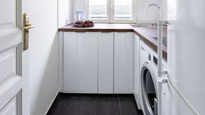A compact kitchen with a washing machine, a window with blinds, and a pendant light. - Modern#ArcDeTriomphe#4people#ChampsÉlysées (Paris)