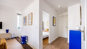 A modern hotel room with a bed, a TV, a blue cabinet, and a hallway leading to another room. - 3. Apartment - 2 people - 1 bedroom - Mouffetard - Sorbonne (Paris)