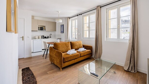 A modern apartment with a sofa, a glass coffee table, a kitchen area, and large windows. - 3. Apartment - 2 people - 1 bedroom - Mouffetard - Sorbonne (Paris)