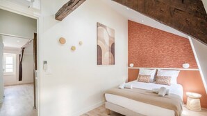 A bedroom with a bed, a wooden ceiling, and a textured wall. - 5. Two bedrooms#Champs-Élysées#Arc de Triomphe#AC (Paris)