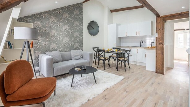 A modern living room with a sofa, coffee table, and a dining area with chairs. There is a kitchen with white cabinets and a clock on the wall. - 5. Two bedrooms#Champs-Élysées#Arc de Triomphe#AC (Paris)