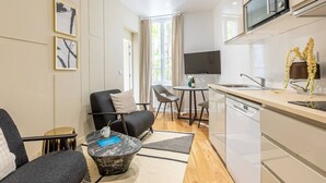 Uma cozinha moderna com micro-ondas, uma sala de jantar com mesa e cadeiras, um sofá e uma mesa de centro.