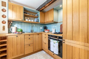 Una cocina con armarios de madera, un fregadero, una estufa y una encimera con varios objetos.
