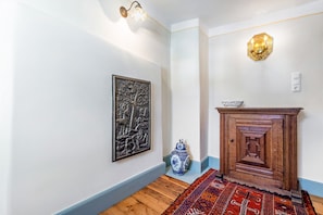 Un pasillo con un aplique en la pared, un adorno decorativo, un armario de madera y una alfombra estampada.
