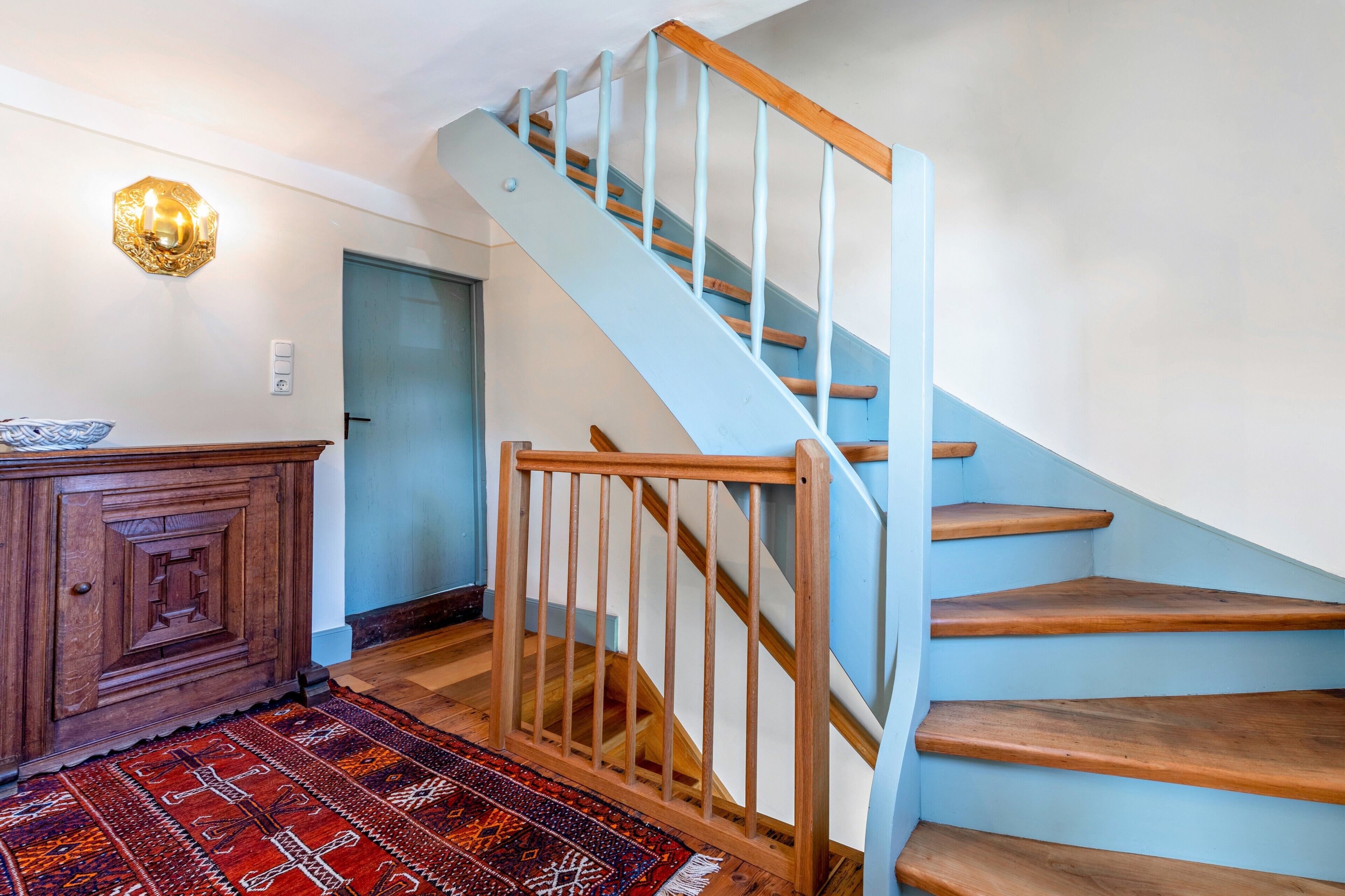 Eine Treppe mit Holzhäusern und einem blauen Geländer, die zu einer Tür führt.