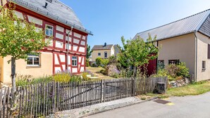 A traditional half-timbered house with a wooden fence and a stone wall in the foreground.