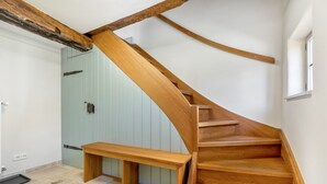 A wooden staircase with a built-in bench at the bottom, leading to a room with a light blue door and a window.