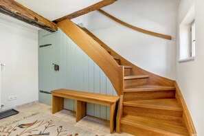 A wooden staircase with a built-in bench at the bottom, leading to a room with a light blue door and a window.
