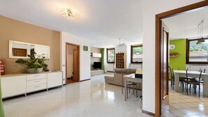 Ein geräumiger Wohnbereich mit einer Couch, einem Esstisch und einer Küche im Hintergrund.