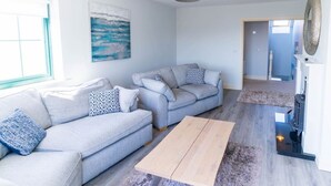 Ein modernes Wohnzimmer mit einer grauen Sofagarnitur, einem Holztisch und einem Kamin.