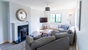 Ein modernes Wohnzimmer mit Kamin, Flachbildfernseher, Sofa und Couchtisch.