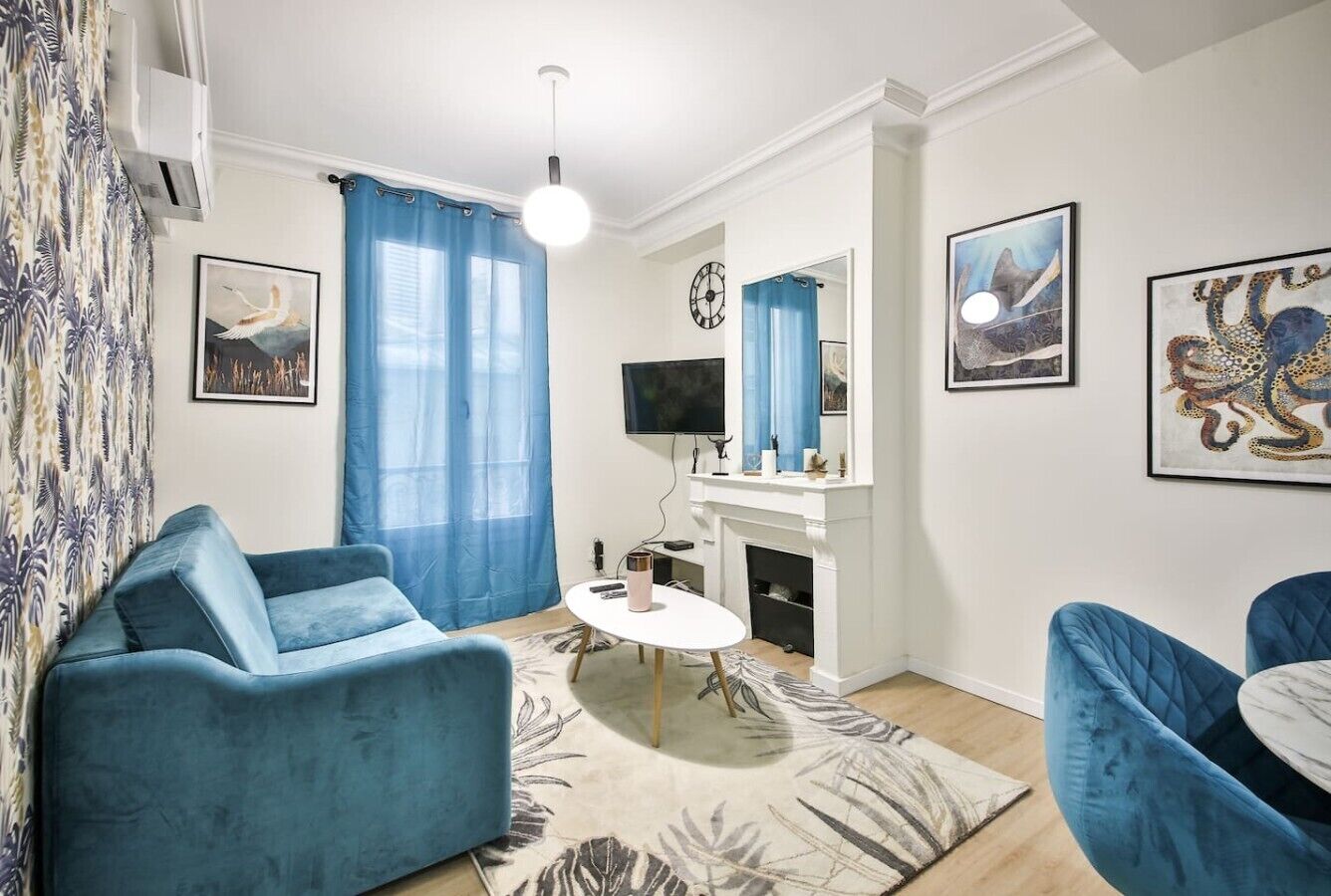 A living room with a sofa, a coffee table, a fireplace, and artwork on the walls.