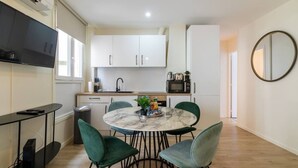 Une cuisine moderne avec des meubles blancs, un four à micro-ondes et un évier. On y trouve une table à manger avec quatre chaises et une petite plante posée dessus.