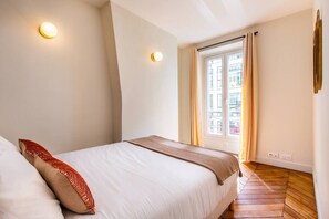 A bedroom with a bed, a window with curtains, and two wall-mounted lights. - 3. Two bedrooms#Champs-Élysées#Arc de Triomphe#AC (Paris)