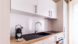 Een moderne keuken met witte kasten, een zwart aanrecht, een koffiezetapparaat en een spoelbak.