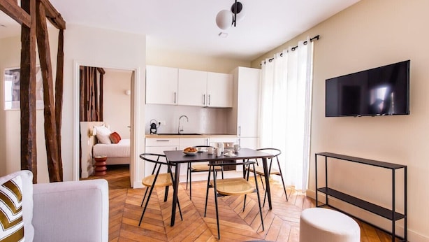 Een modern appartement met een eethoek, keuken en een aan de muur bevestigde televisie.