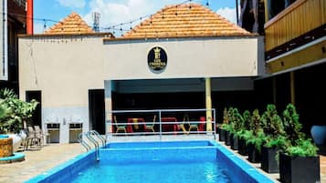 A hotel with a swimming pool, outdoor seating, and a sign reading 'LUX PRIMER HOTEL.'