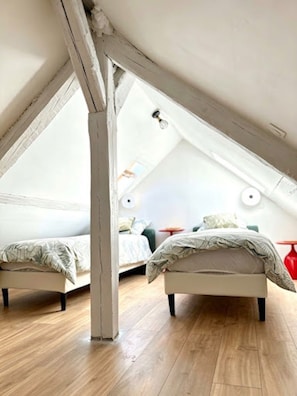 Ein Schlafzimmer mit zwei Betten, Holzboden und einer schrägen Decke.