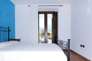 A bedroom with a bed, a window with curtains, and a view of the outside.